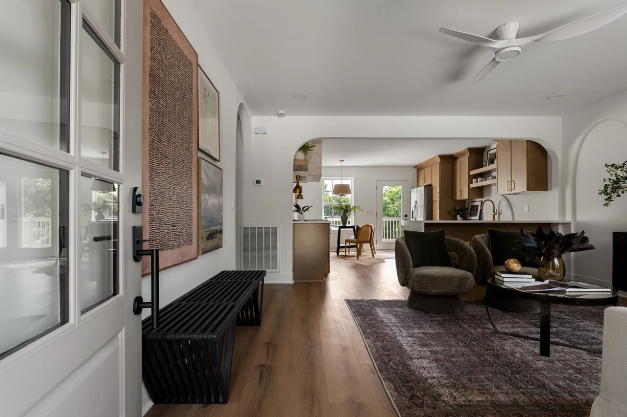 Entry with black bench, framed art and view through an arch to the kitchen