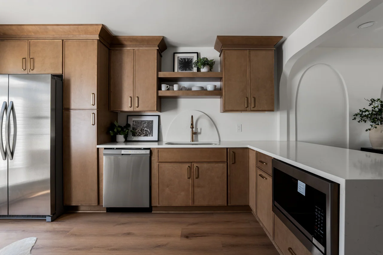 Kitchen cabinetry with brass hardware, arched backsplash and stainless appliances