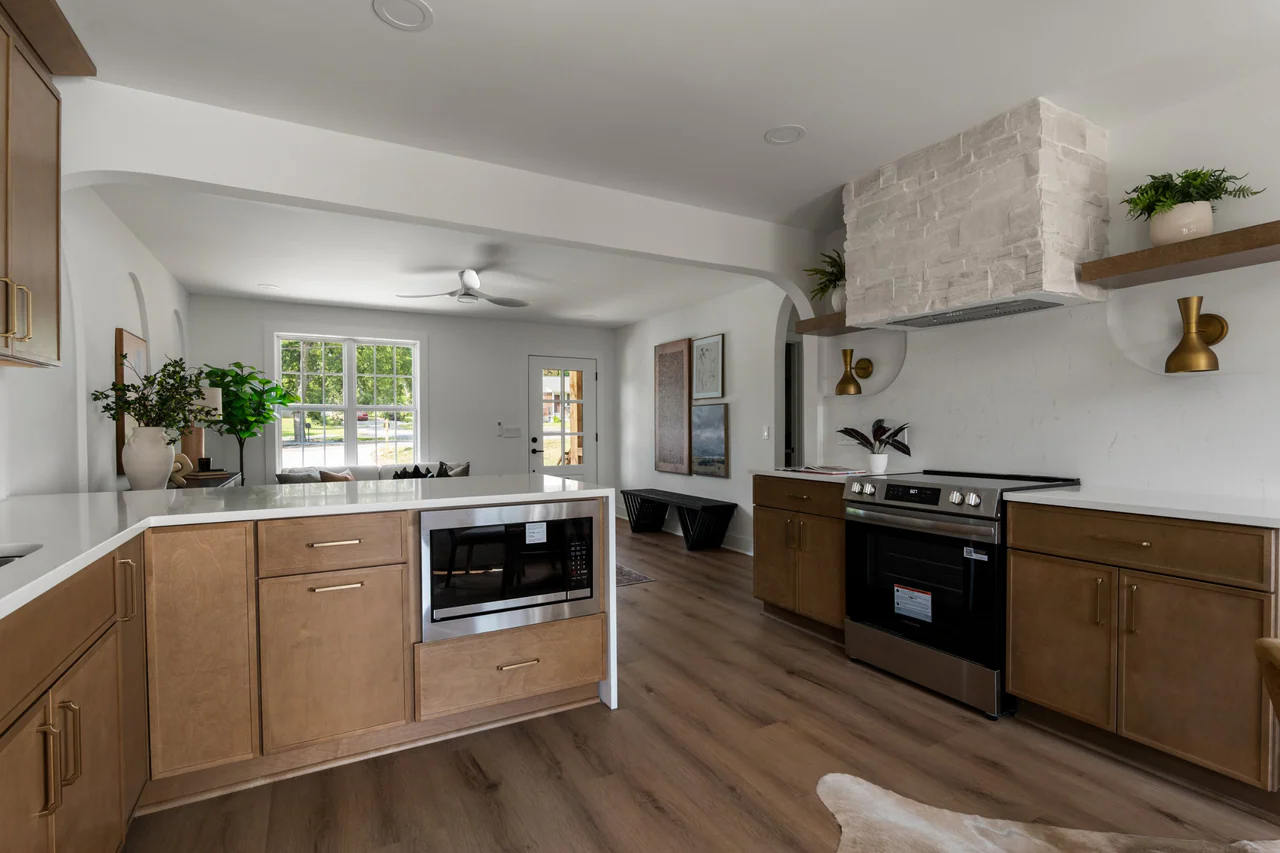 Kitchen and living room beyond, with stone range hood and waterfall counter