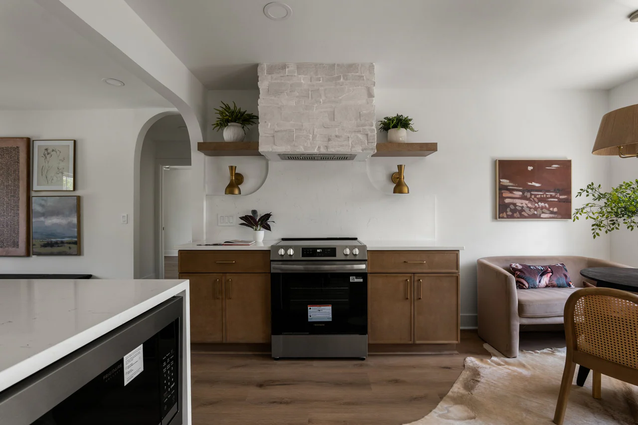 Range wall with stone hood, floating shelves and brass sconces