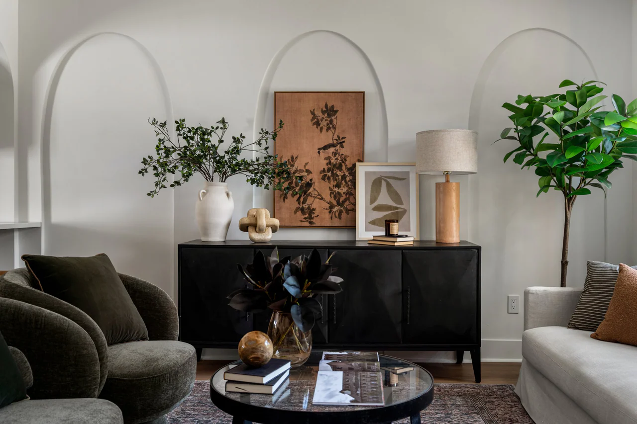 Black sideboard styled with art and lamp against arched wall details