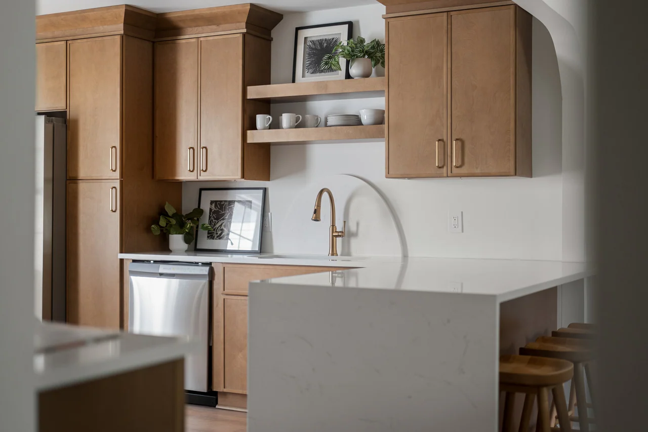 Kitchen cabinetry, brass faucet and waterfall counter