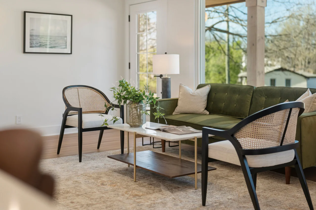 Cane-back chairs and green sofa around a marble coffee table