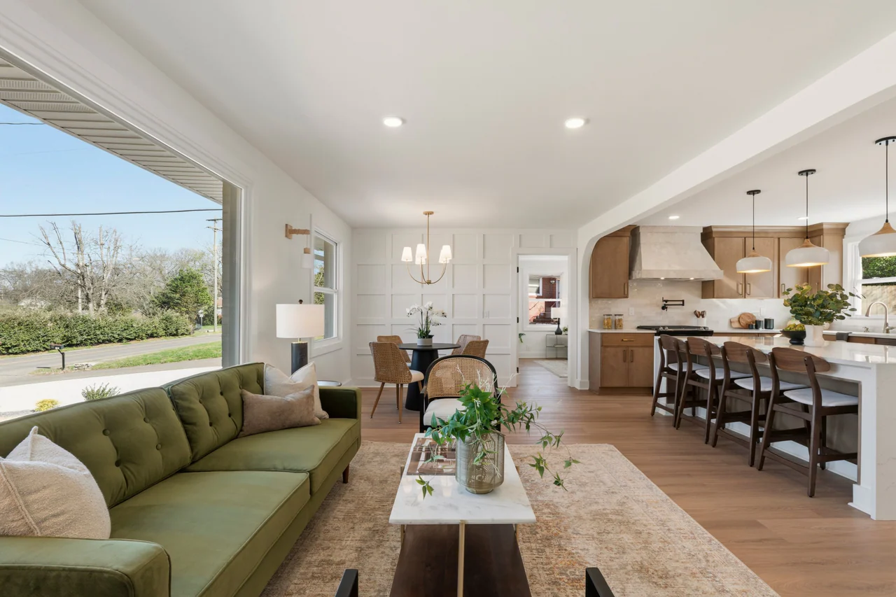 Living room with green sofa opening to the dining area and kitchen