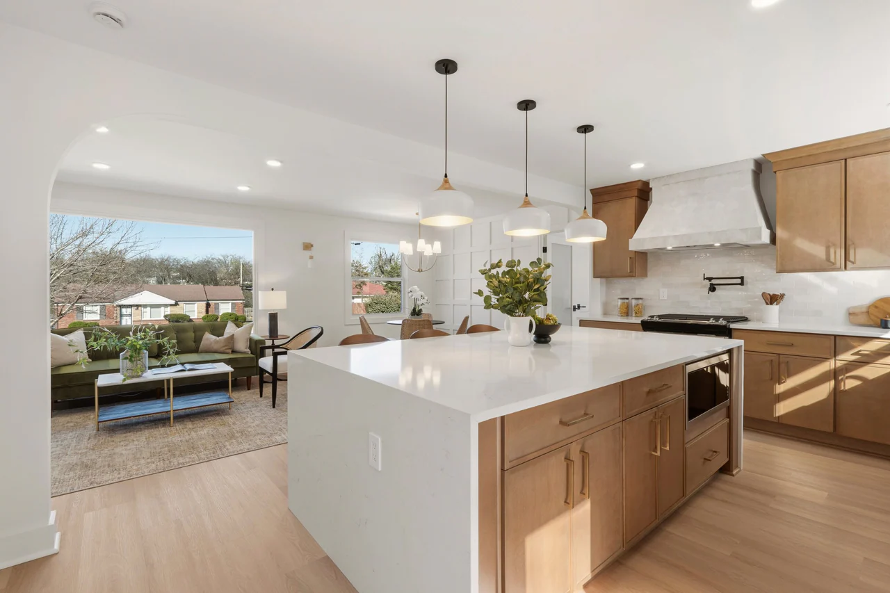 Waterfall kitchen island with the living room beyond an arched opening