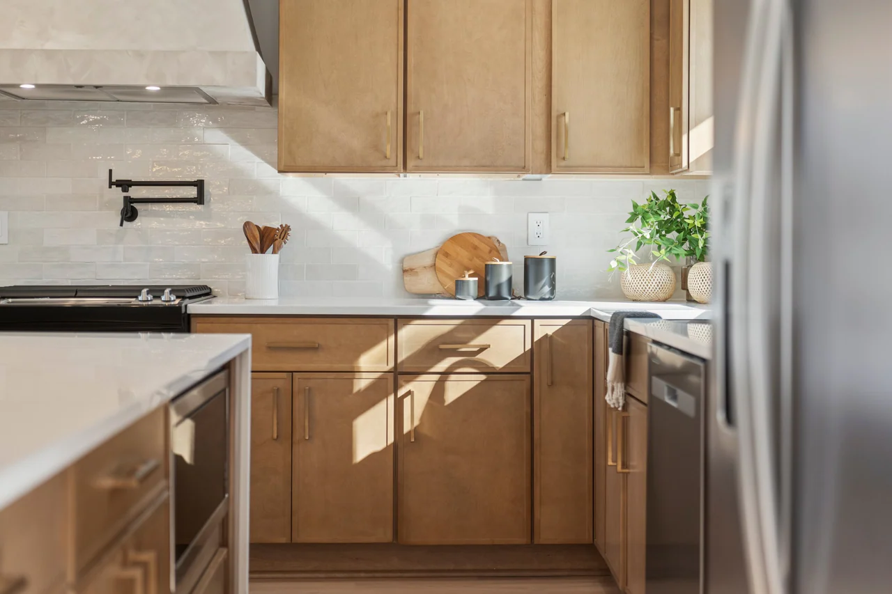 Wood cabinetry, tile backsplash and pot filler in afternoon light