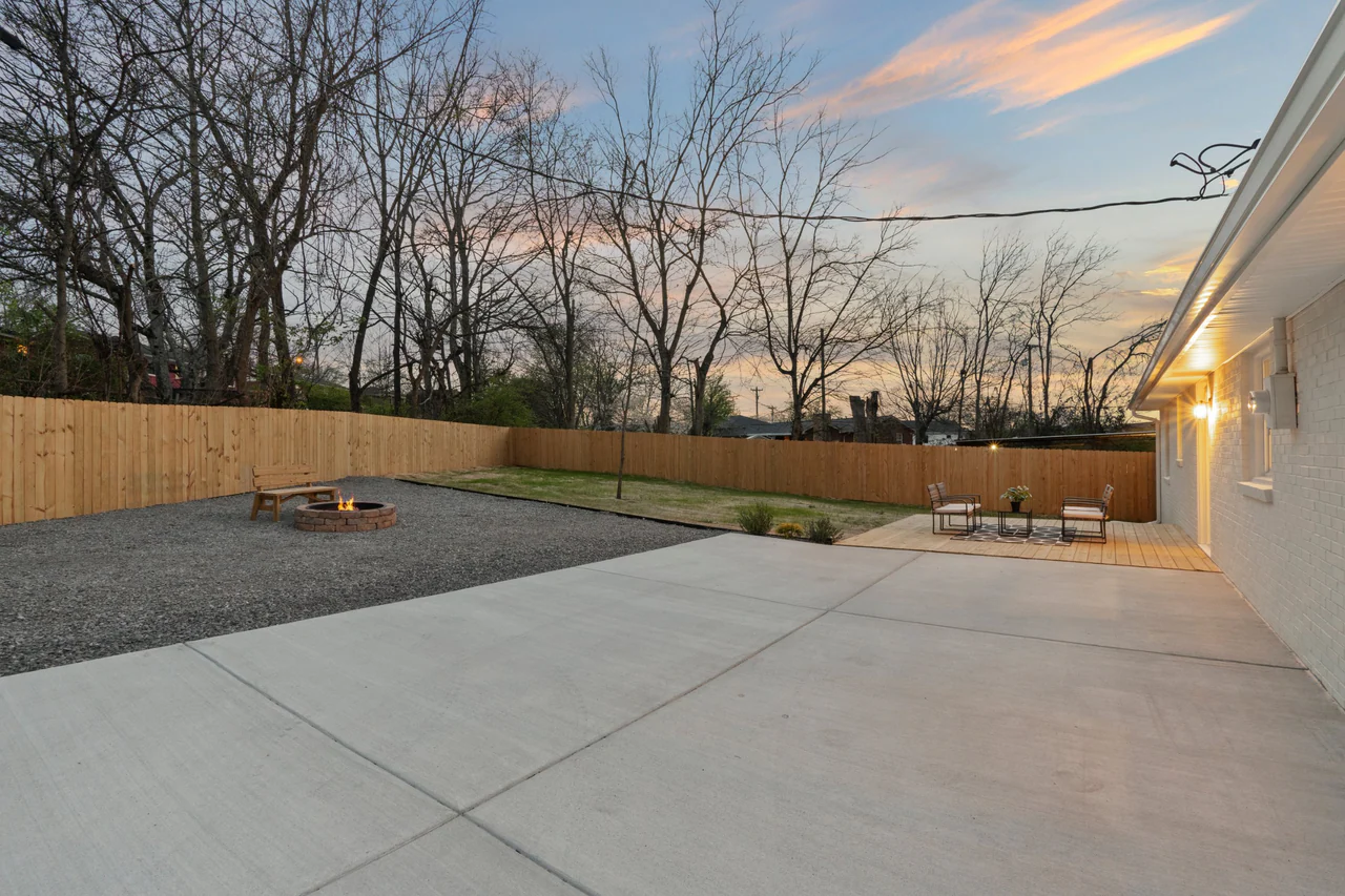 Fenced backyard at dusk with patio, fire pit and deck
