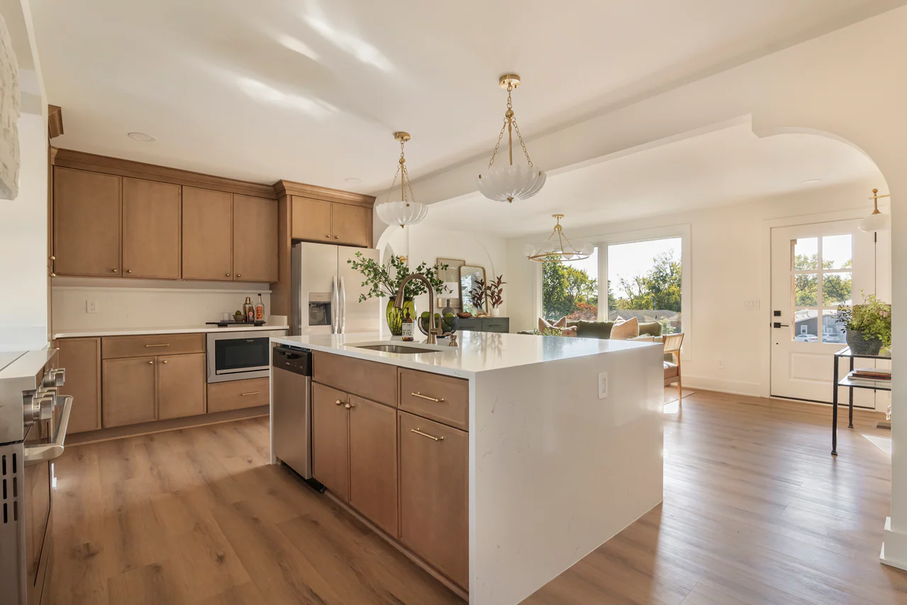 Kitchen with waterfall island, pendant lights and an arch to the living room