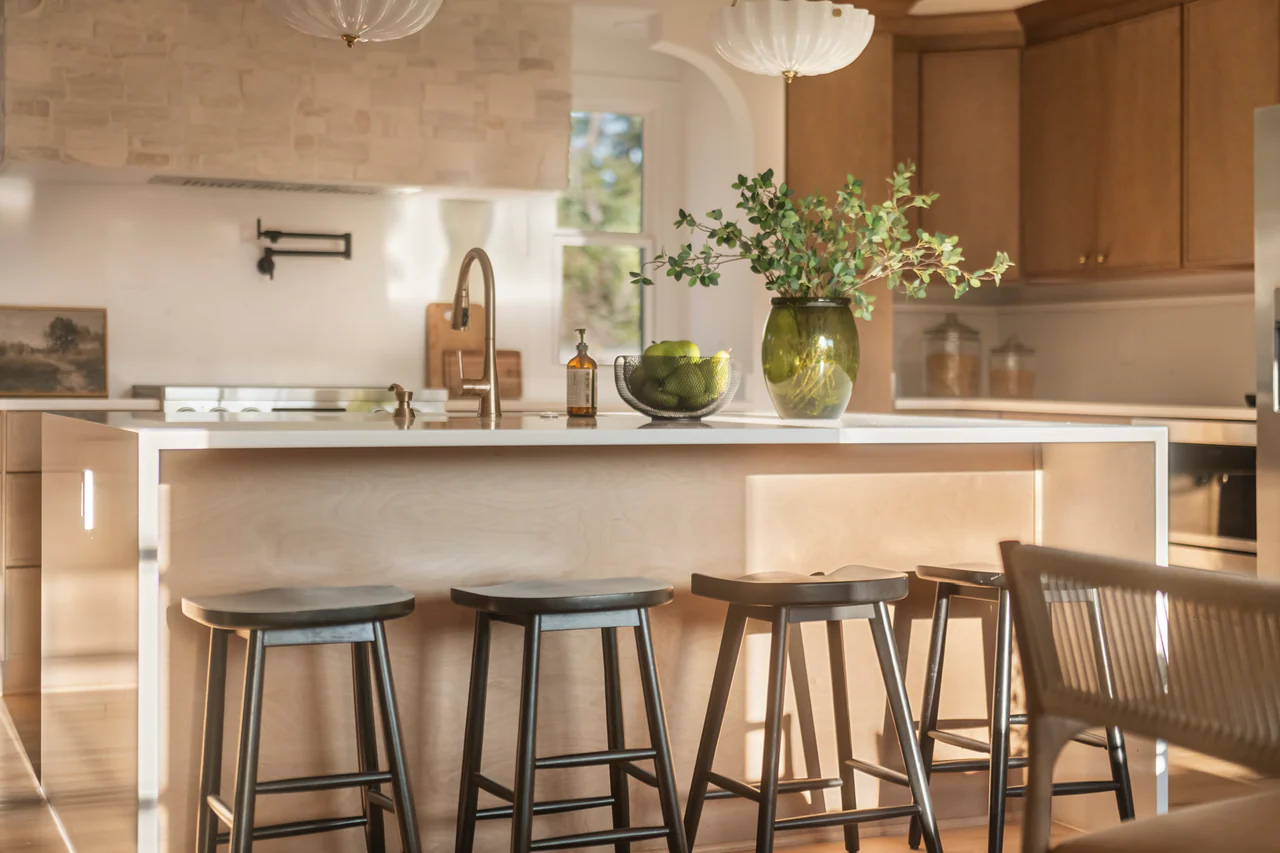 Kitchen island with black stools, stone hood and brass faucet