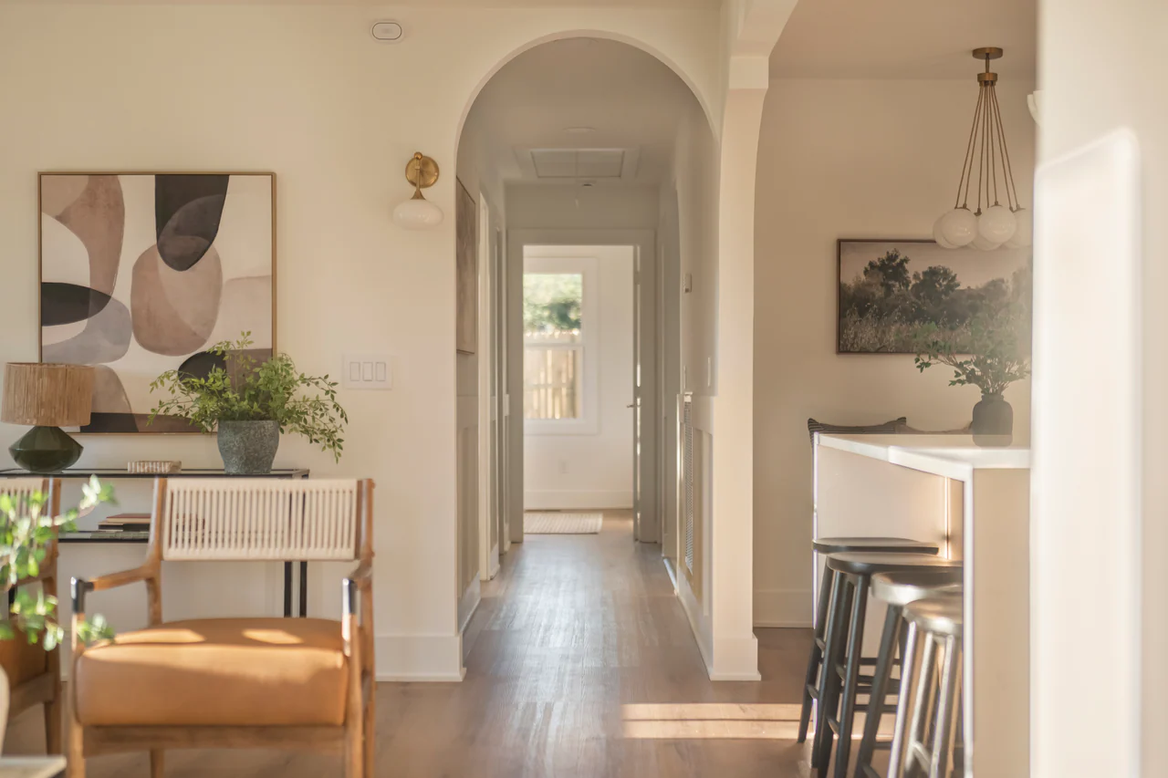 Hallway seen through an arched opening, with abstract art and kitchen stools