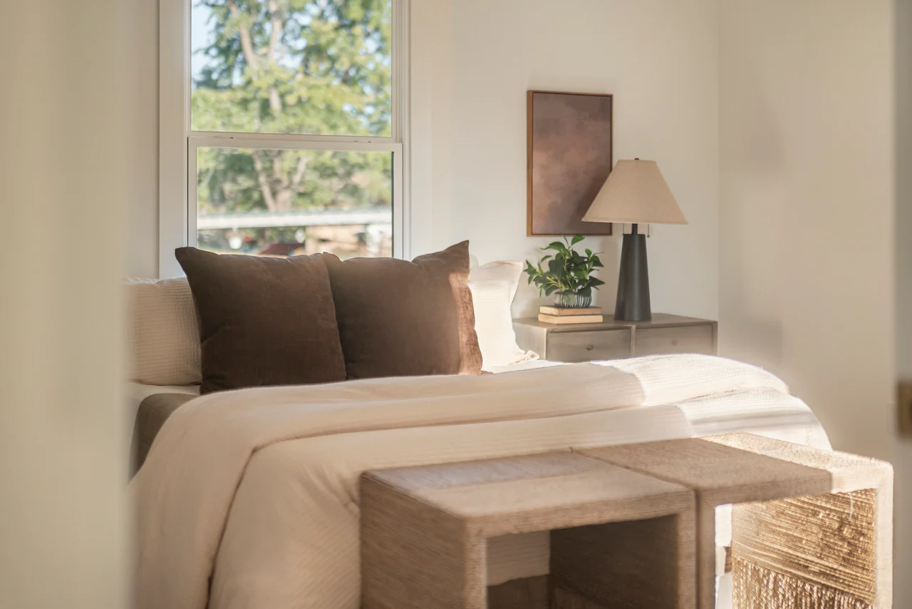 Bed with brown pillows beside a window