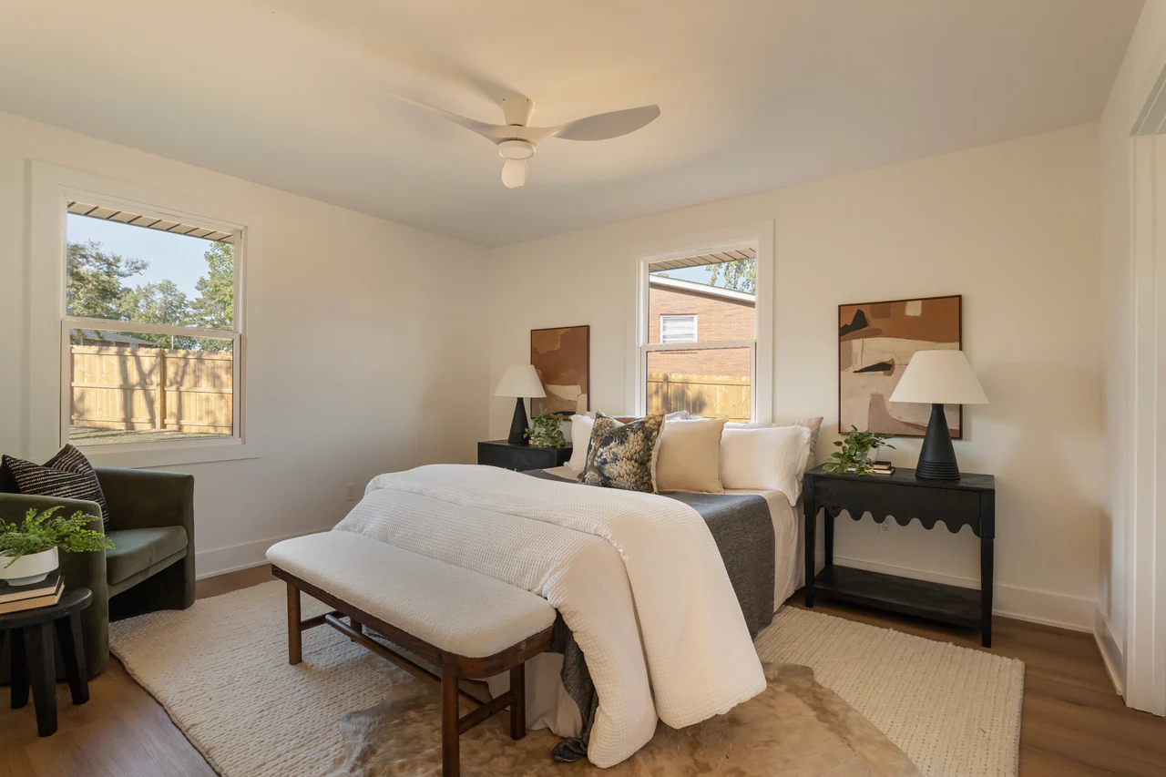 Bedroom with scalloped nightstands, upholstered bench and two windows