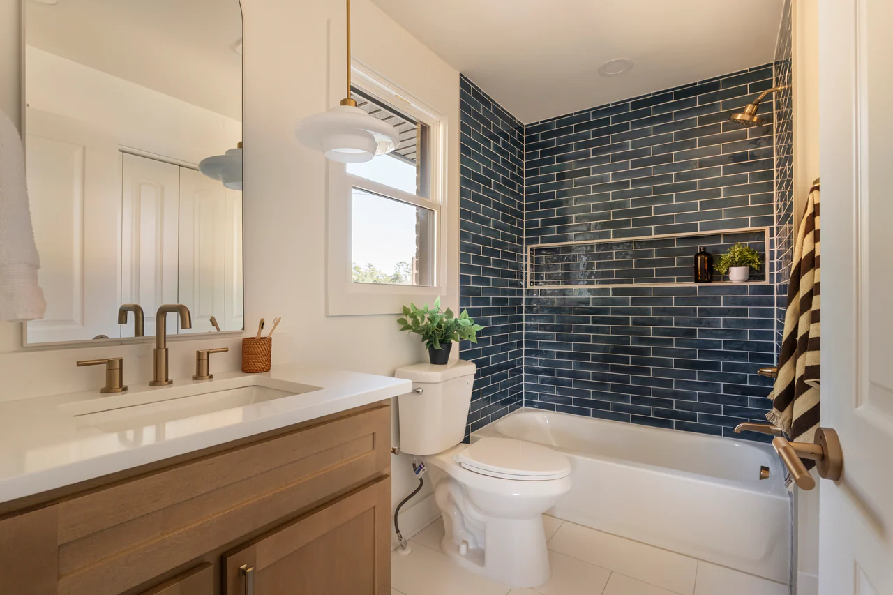 Bathroom with navy tile tub surround and wood vanity