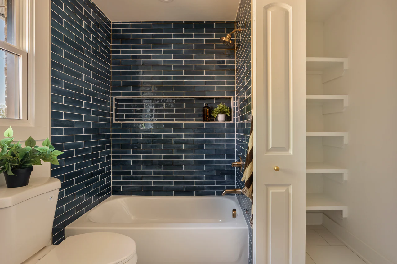 Navy tile tub surround with recessed niche and open shelving